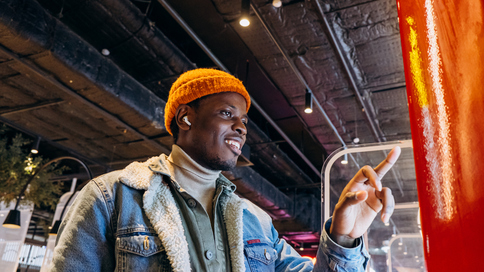 Smiling customer using a self-service kiosk in a restaurant, highlighting the benefits of AI in self-service kiosks for faster checkouts and improved customer experience.